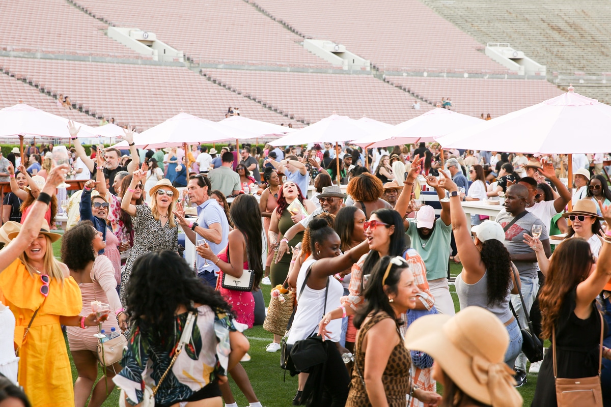 A large group of people dance and mingle at the Rose Bowl