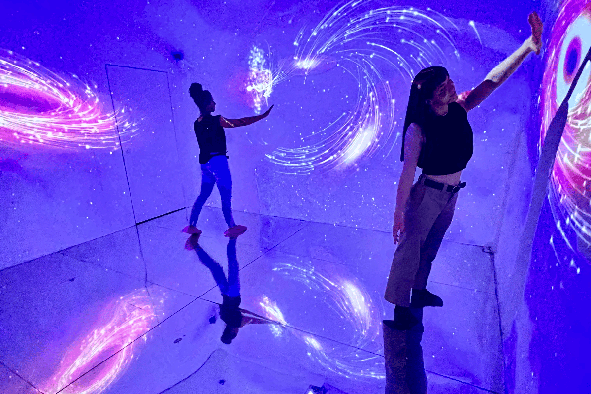 Two people touch walls covered in cosmic light
