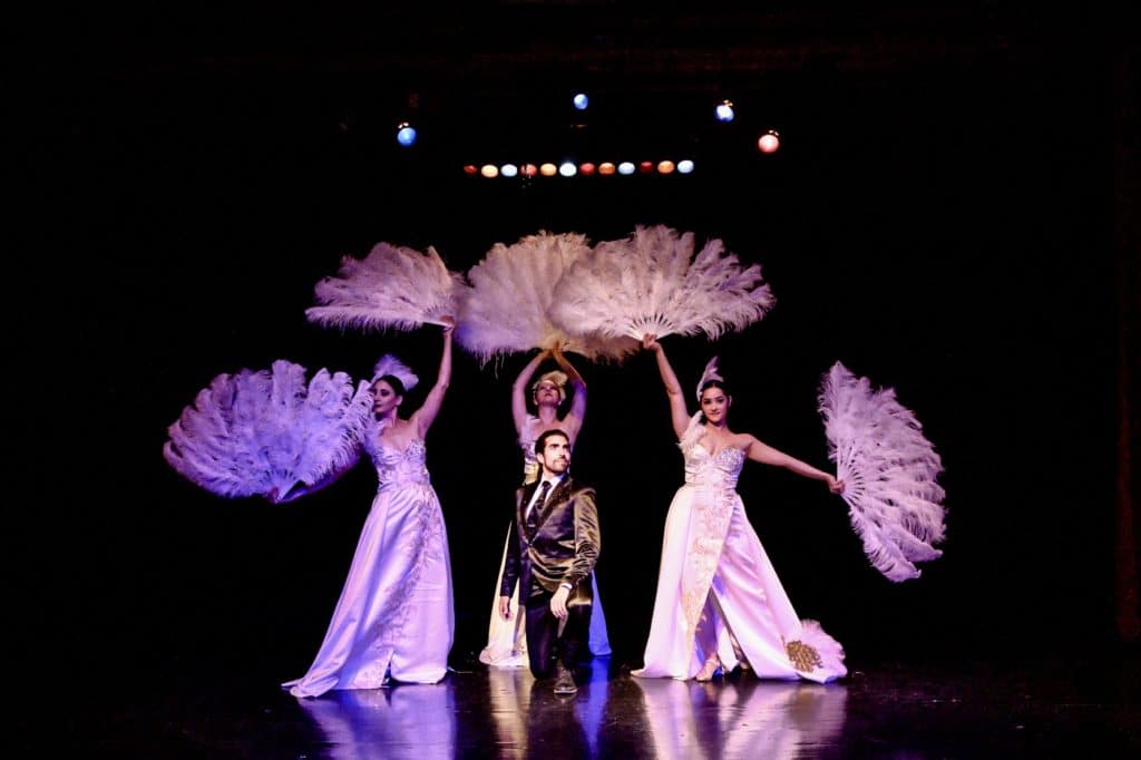 Performers in gorgeous ball gowns perform on-stage at a 