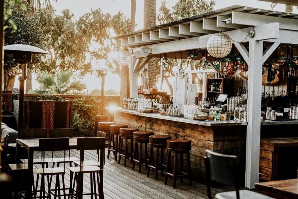 Outdoor bar patio with tree and sun peaking from behind, where actress Eva Longoria is set to bartend