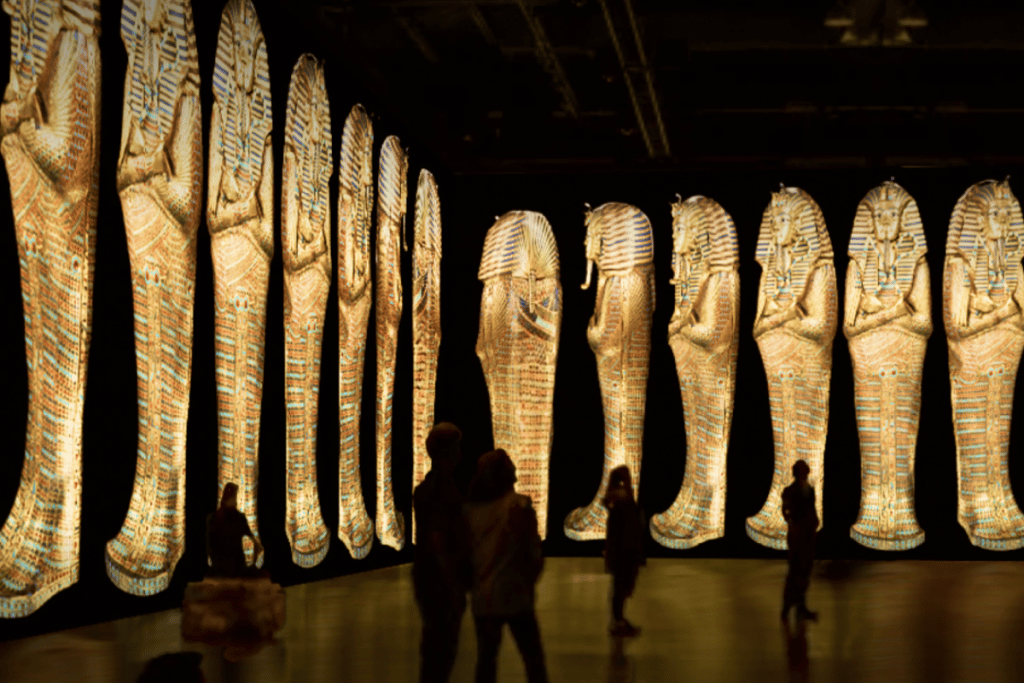 Multiple pictures of sarcophagi surround people as they walk through the exhibit