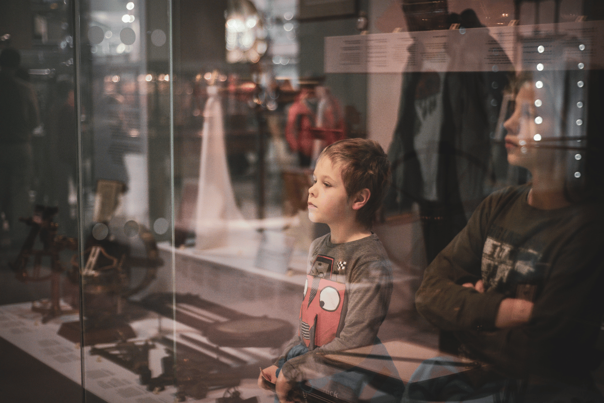 A kid in a museum smushes their face against the glass