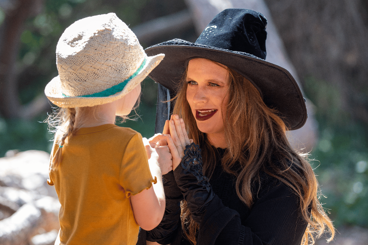 A woman dressed as a witch talks to a child