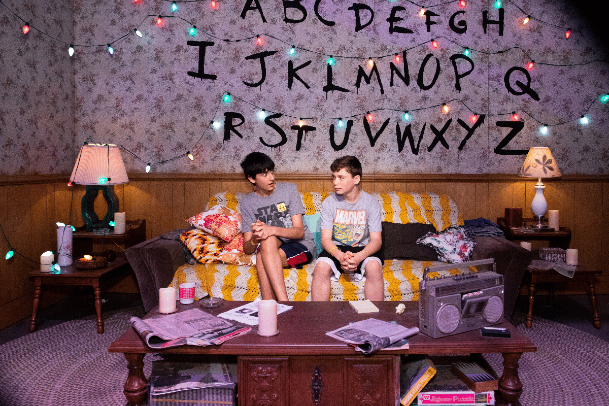 Two teens sitting on a couch at the Stranger Things Experience