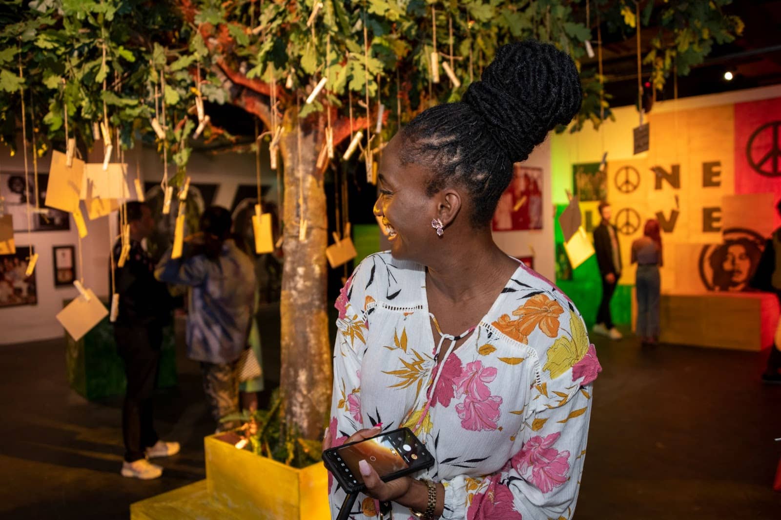A woman smiles beneath a tree at the Bob Marley One Love Experience