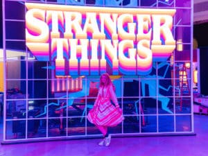 A woman stands in front of a Stranger Things sign