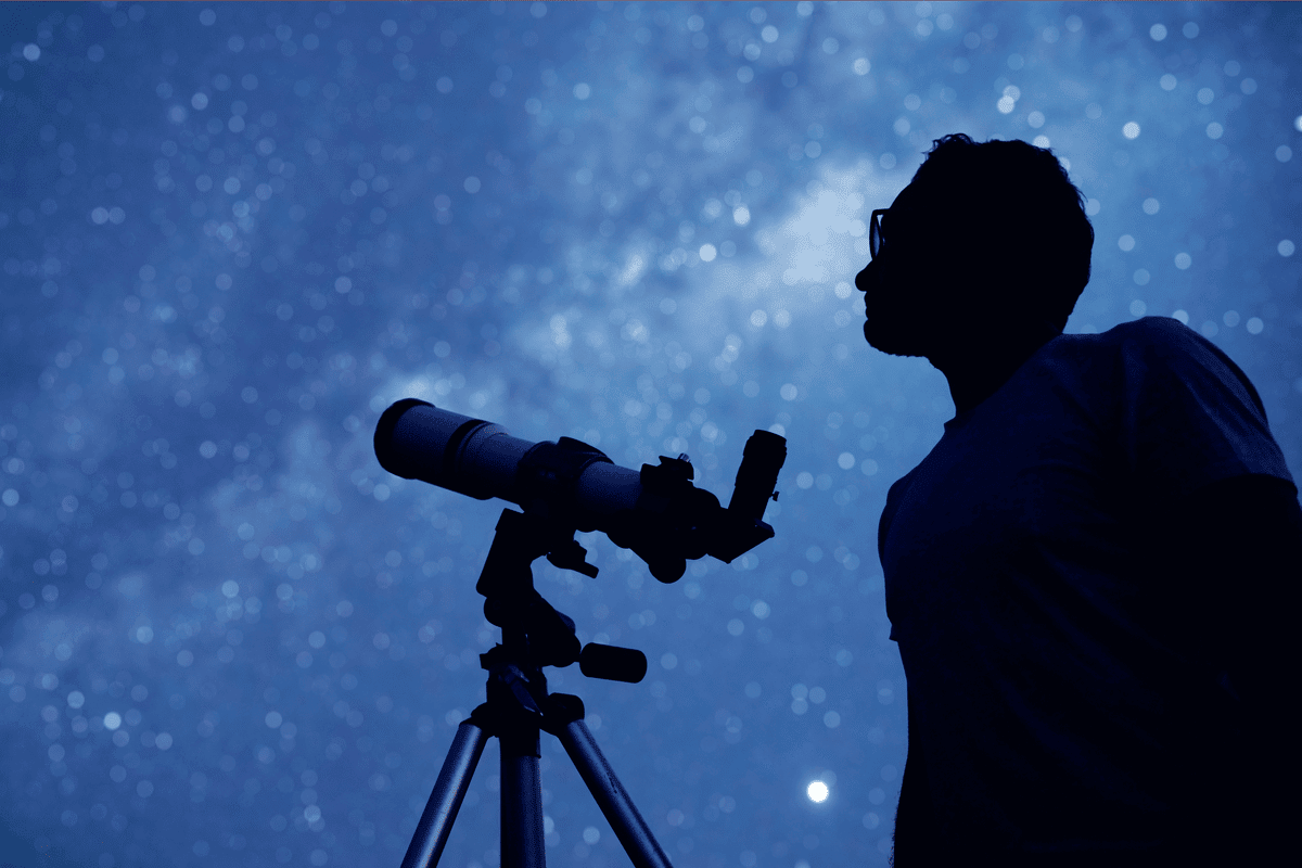 A man looks at the stars with a telescope