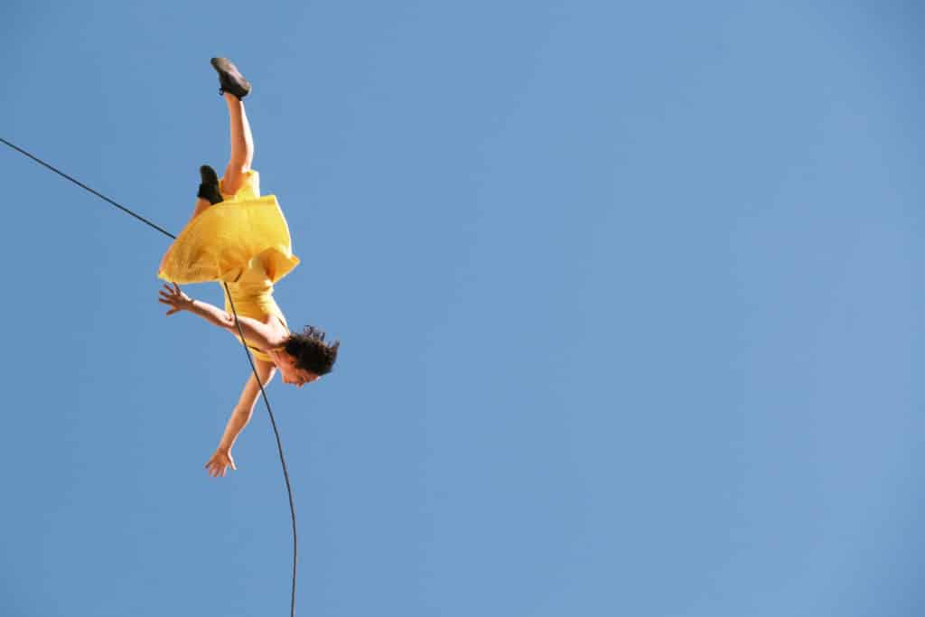 An aerial dancer moves through the air suspended by a rope