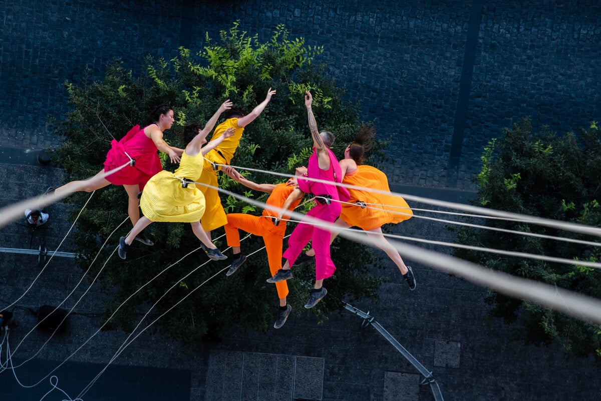 A group of performers dance across the face of a building