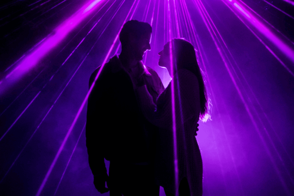 A couple looks lovingly at each other underneath lights