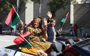 two women wave at camera during Black History month parade in pasadena