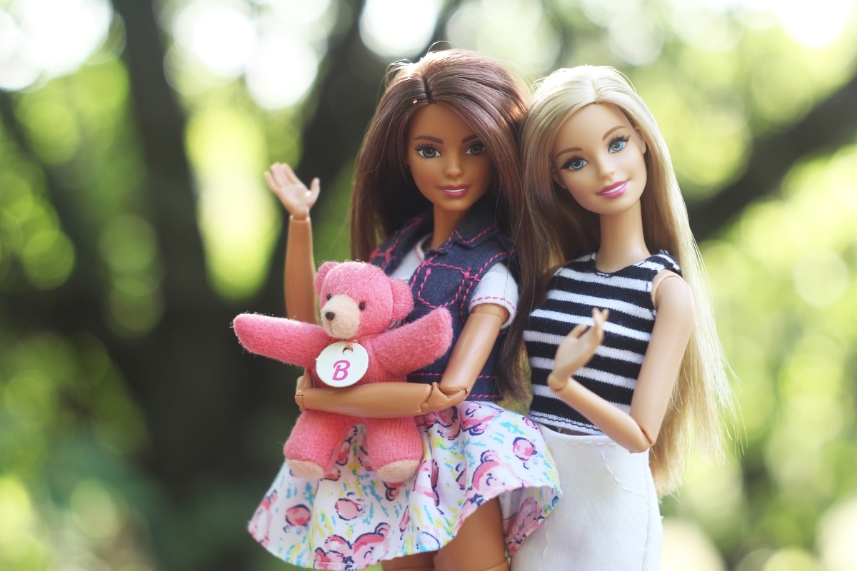 Two Barbie dolls wave at the camera
