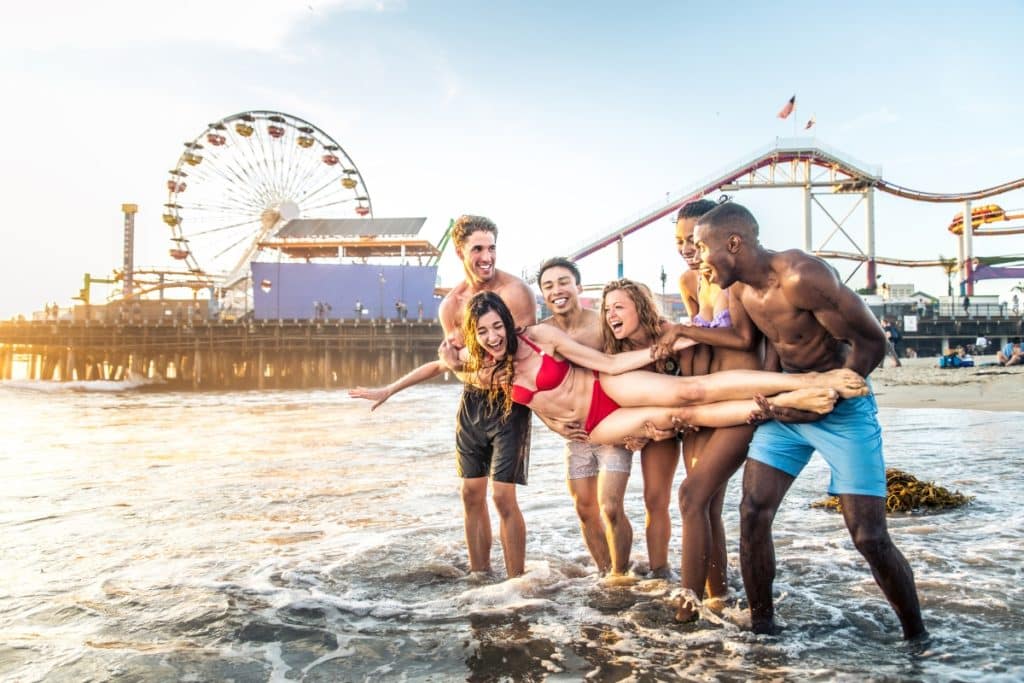 A group of friends laughs in front of the Santa Monica Pier