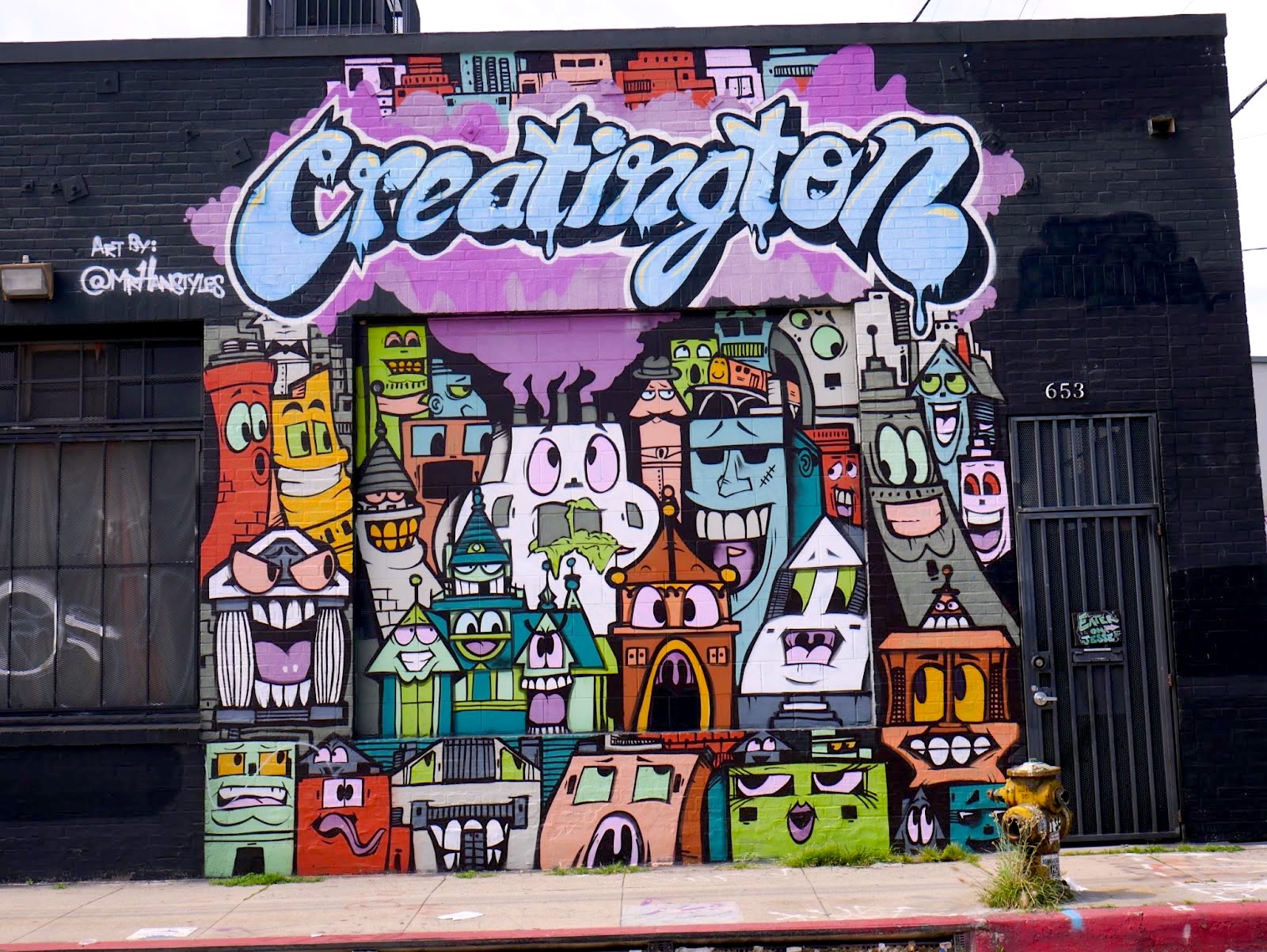 A variety of cartoon buildings with human-like qualities is painted on a building