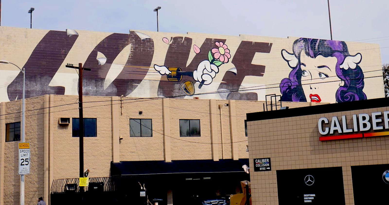 A mural says the word love and shows a cartoon image of a woman with wings sticking out of her head