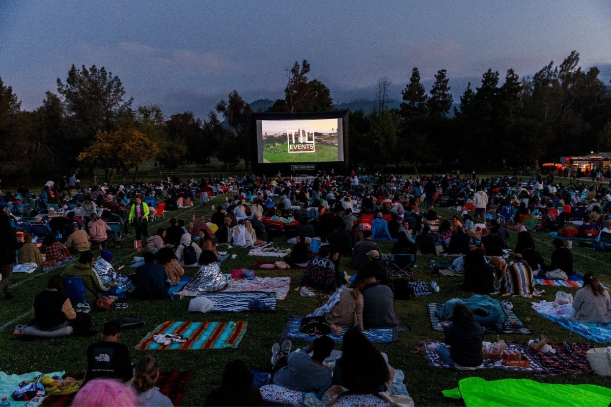 A crowd of people watches a movie outdoors