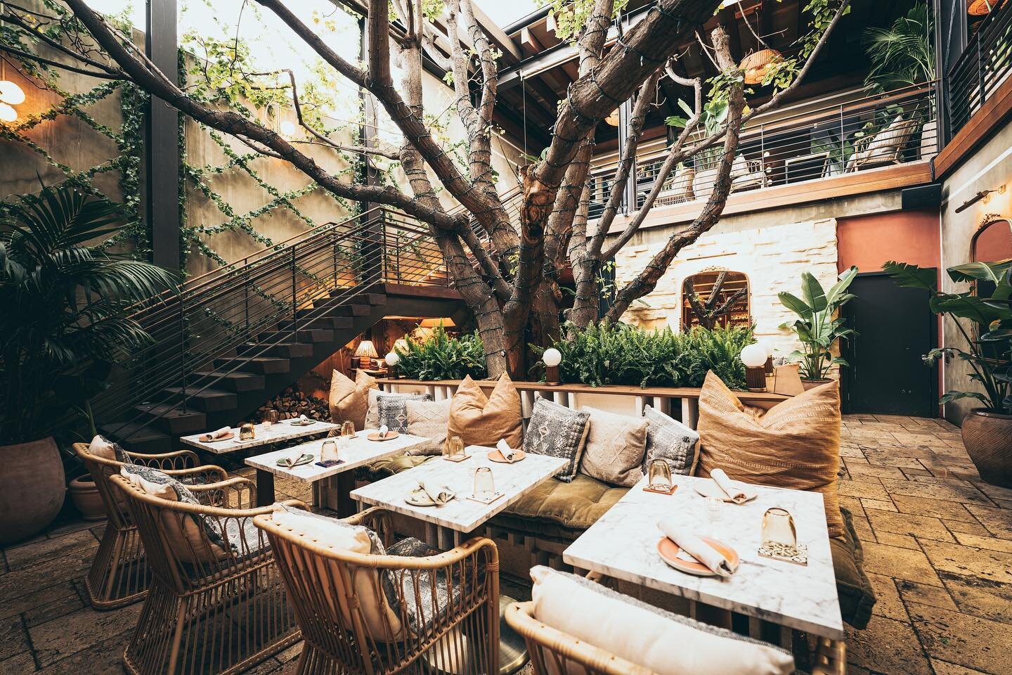patio exterior de Mírate Los Ángeles con decoración bohemia, un árbol, sofá y mesas