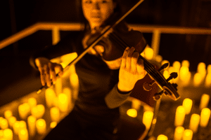 A violinist performs, currounded by candles at a Candlelight concert. 