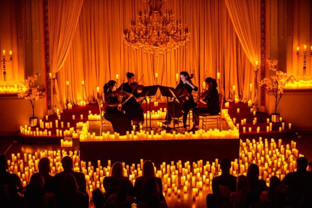 A striking photo of an intimate concert stage surrounded in candles.