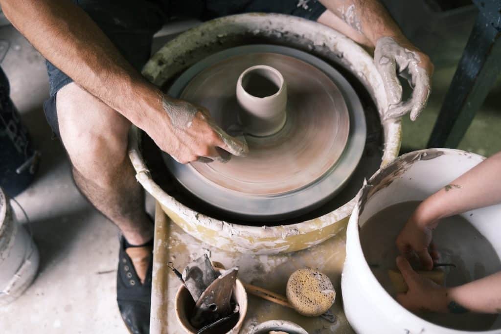 A close-up of hands at a pottery wheel.