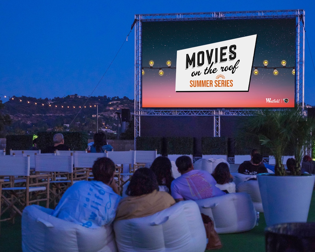 A nighttime view of a screening of Movies On The Roof. 
