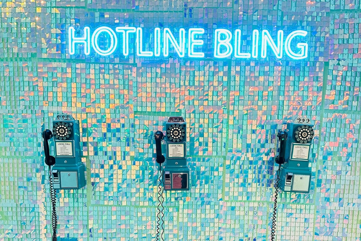 Three payphones sit on a wall that says Hotline Bling