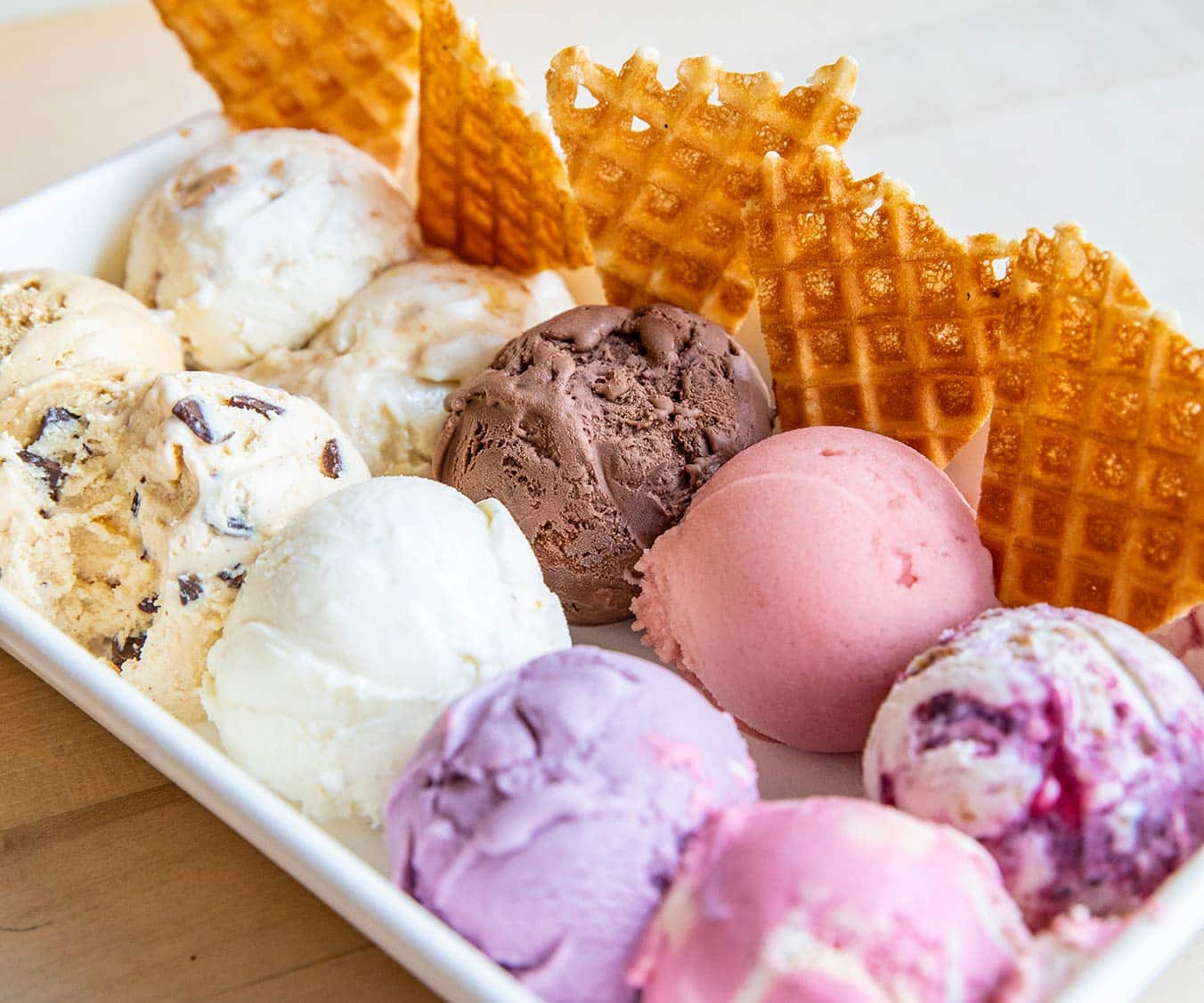 A plate full of ice cream scoops and waffle cones.