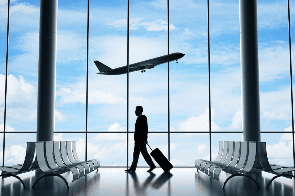 man with luggage at airport and a plane flying in the distance