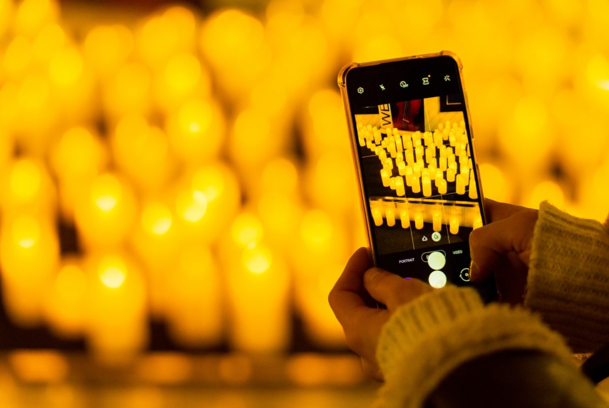 Dos manos sujetando un móvil mientras toma una foto de las velas